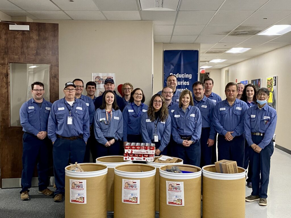 Daikin Employees stand behind barrels filled with donations for the community